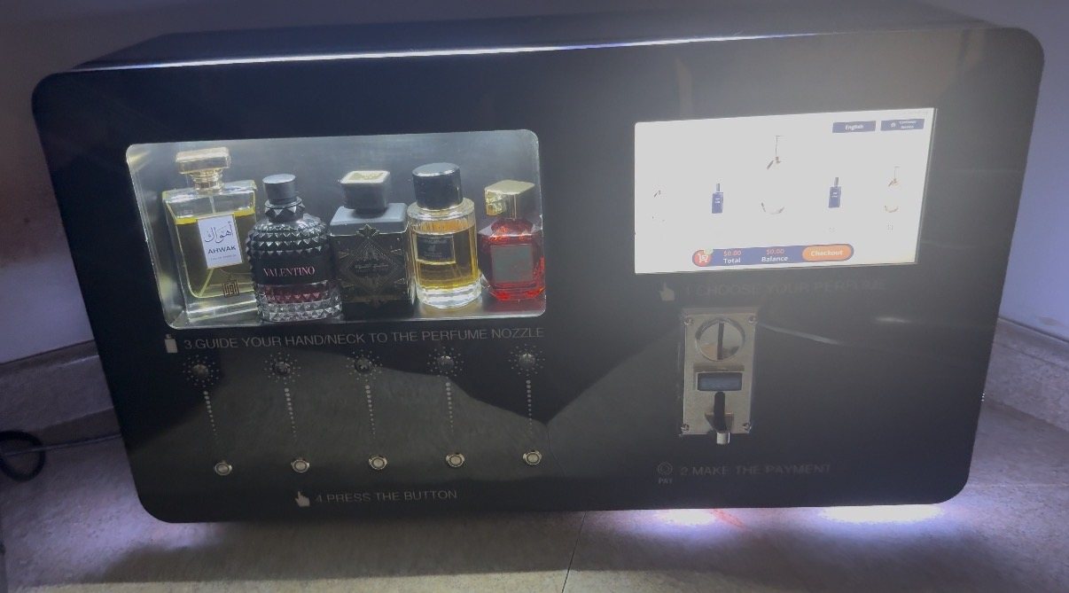 SCENTLÉ machine in gloss black, five fragrance bottles lit behind glass beside the touchscreen