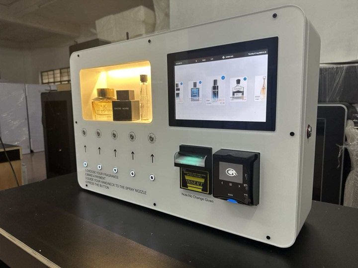 SCENTLÉ fragrance vending machine: lit display of five fragrance bottles, colour touchscreen, bill acceptor and contactless card reader